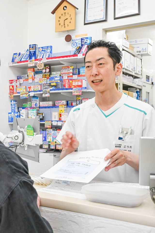 ごうだ薬局のカウンターで、薬剤師がお薬の説明をしている様子