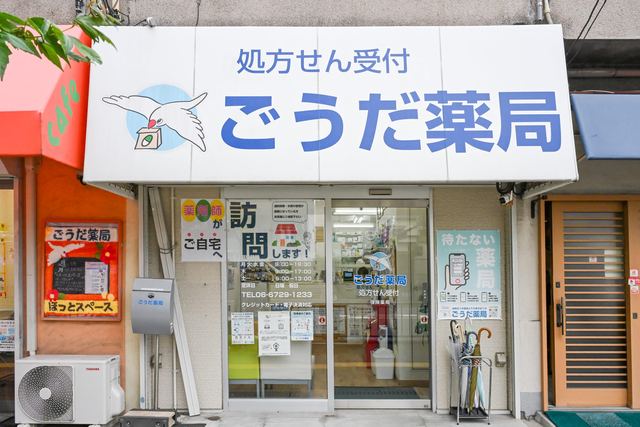 ごうだ薬局の外観。白い看板に青い文鳥のロゴと「処方せん受付 ごうだ薬局」の文字